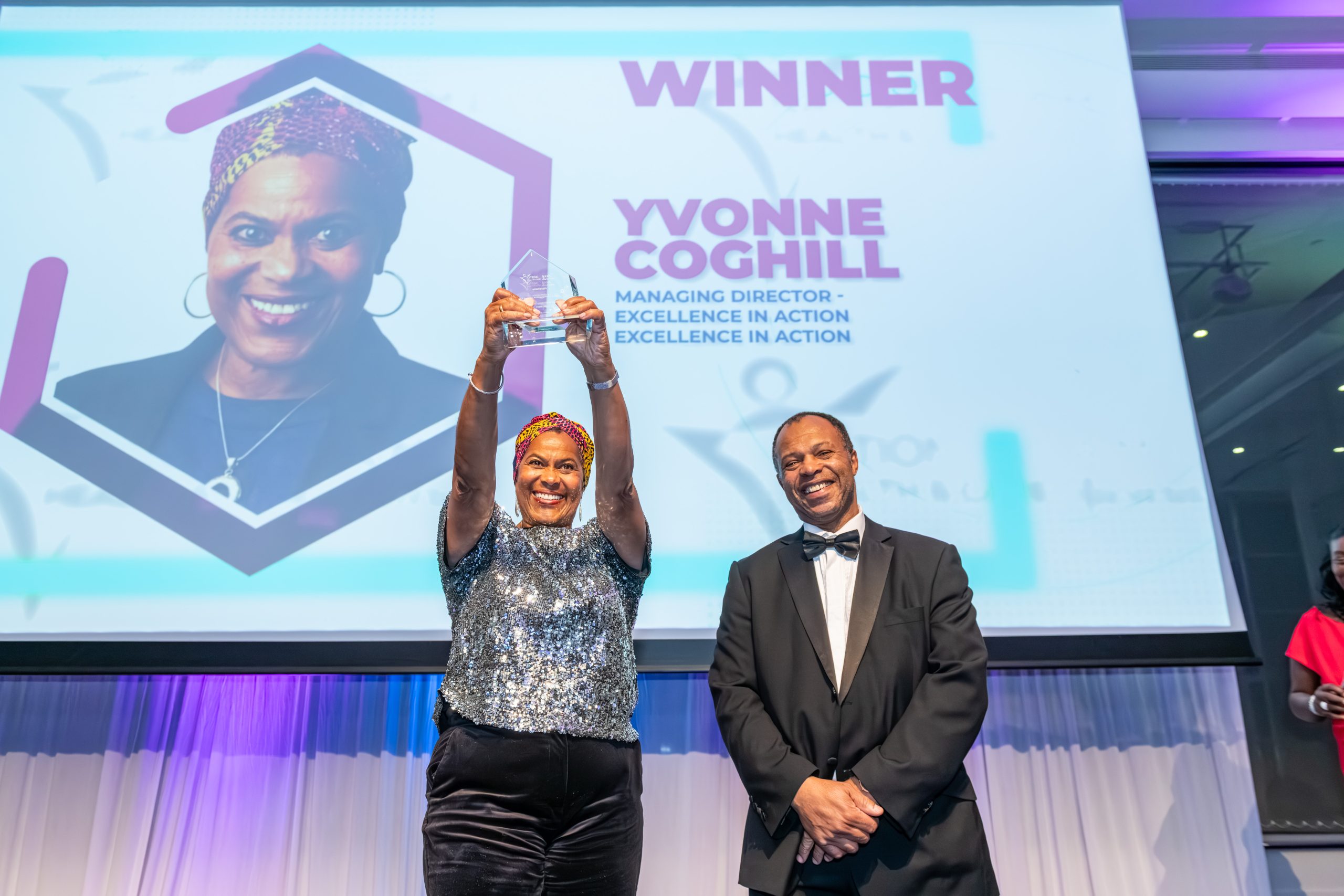 Award winner raising a trophy on stage during the National B.A.M.E Health and Care Awards